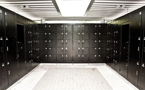Archive photograph of black theme-park lockers arranged around three sides of a covered paved area.