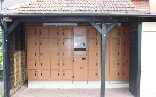 Archive photograph of brown theme-park lockers and a central kiosk beneath a timber canopy.
