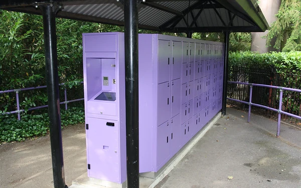 Archive photograph of purple theme-park lockers with a recessed kiosk beneath a metal canopy.