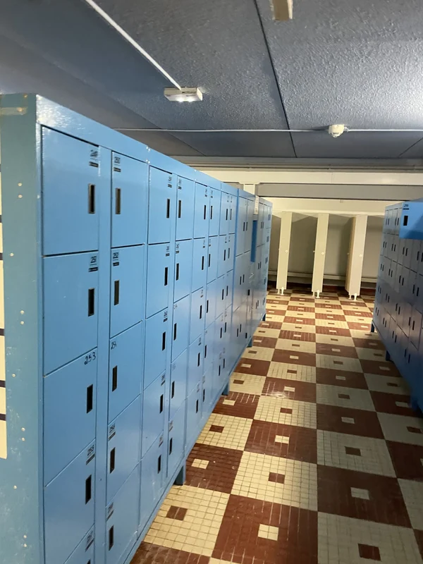 Archive photograph of blue water-park lockers lining an aisle beside changing cubicles.