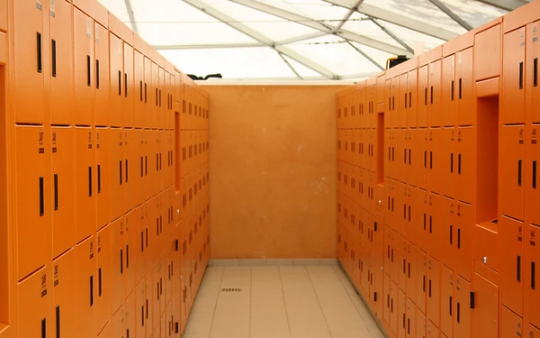 Archive photograph of orange water-park lockers on both sides of a tiled aisle beneath a light roof.