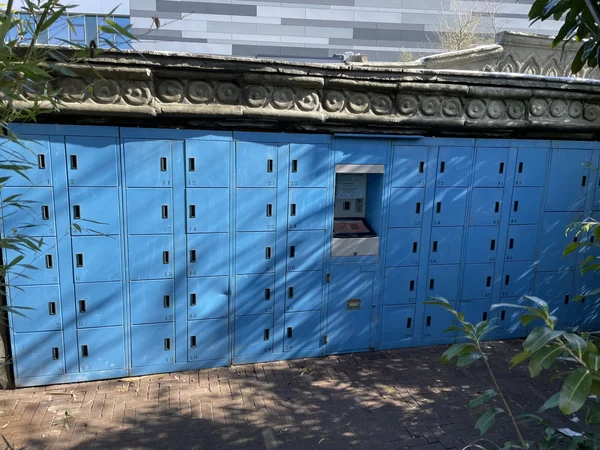 Archive photograph of blue zoo lockers with a recessed kiosk beneath a decorative shelter.