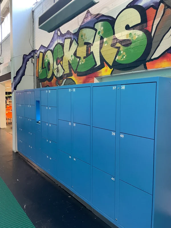 Blue self-service lockers beneath locker signage in a trampoline park.