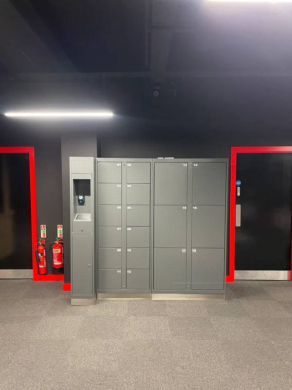 Compact grey electronic locker bank with small and large compartments between two doorways.