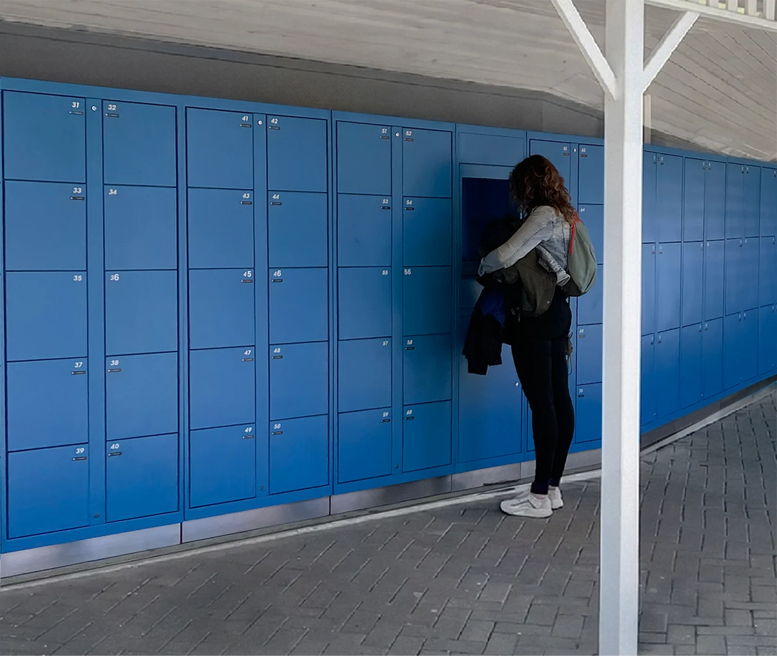 Guest using the touchscreen kiosk at a blue self-service locker bank