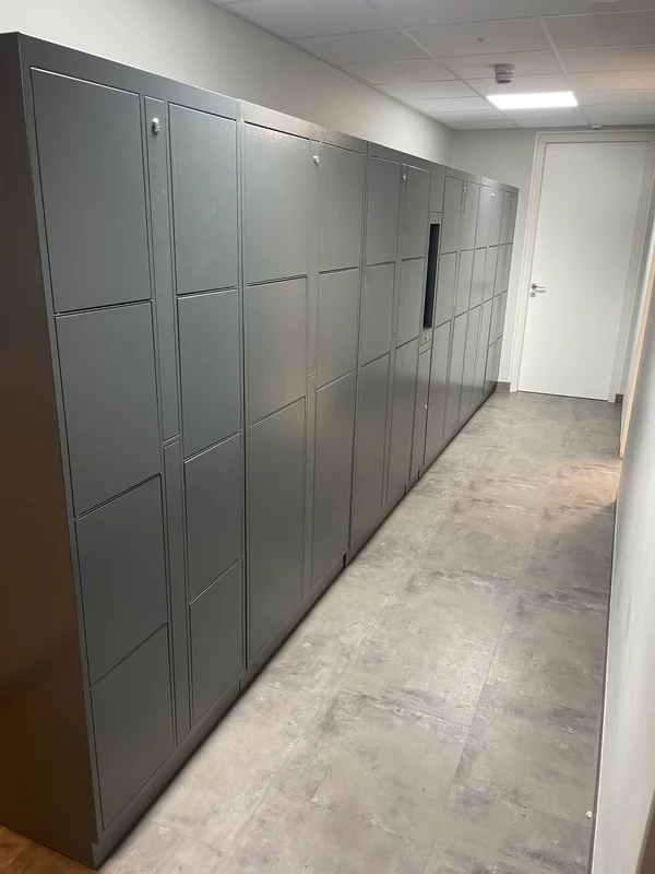 Grey numbered lockers along a bright hostel corridor.